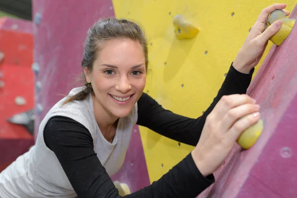 Young beautiful woman climbing a wall — Stock Photo, Image