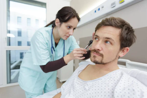 Лікар вивчає пацієнтів внутрішнє вухо в лікарняному ліжку — стокове фото