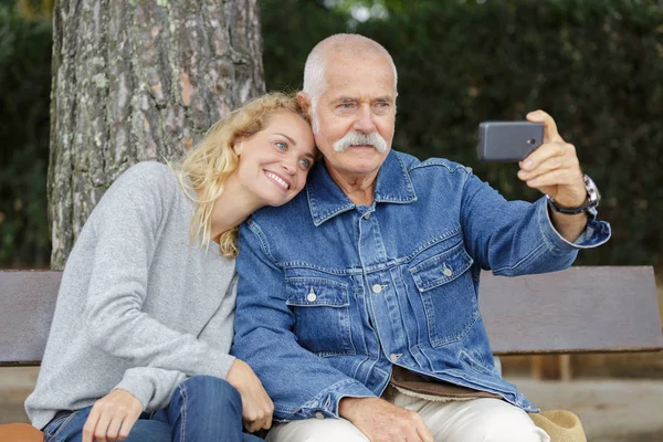 Emekli baba ve orta yaşlı kız dışarıda selfie çekiyorlar. — Stok fotoğraf