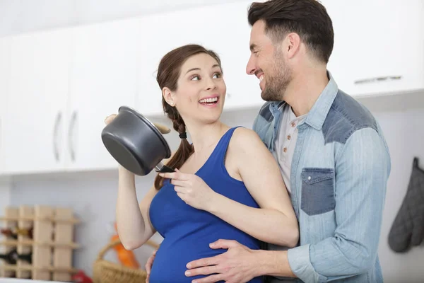 怀孕的女士和男人在厨房里笑 — 图库照片
