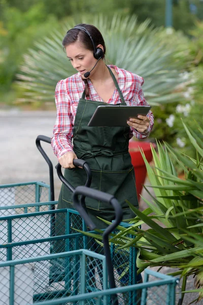 Frau, die in einer Gärtnerei arbeitet, trägt ein Headset — Stockfoto