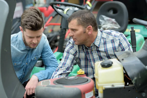 Ingenieur und Lehrling begutachten Rasenmähermotor — Stockfoto