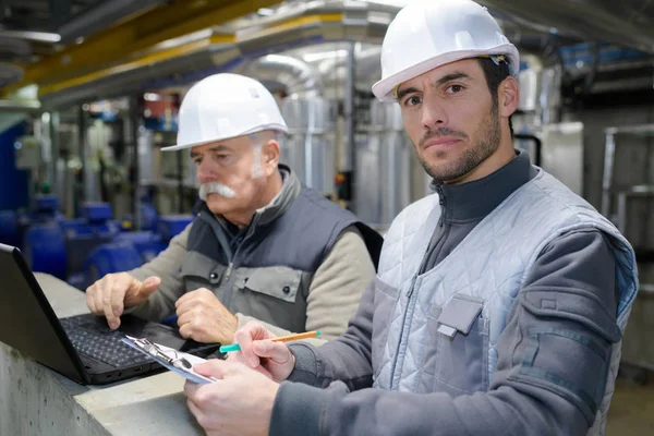 men using laptop in factory