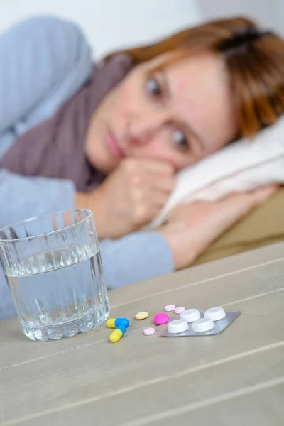 Pastillas frente a la mujer enferma — Foto de Stock