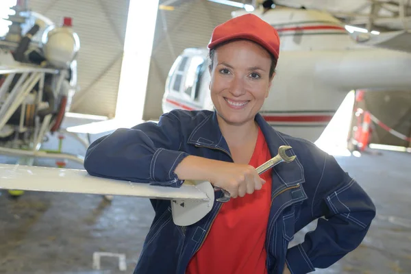 Young female with wrench fixing part of jetliner — Stock Photo, Image