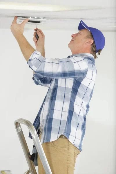 Hombre conduce tornillos en el techo — Foto de Stock