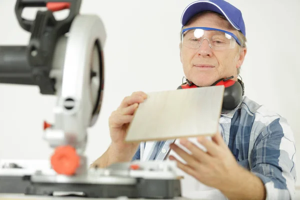 Uomo maturo valutare il legno che ha preparato con sega circolare — Foto Stock