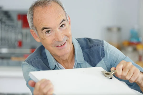 Uomo anziano che lavora su una nuova installazione di cucina — Foto Stock