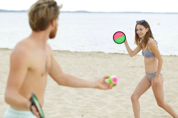 Пара играет в пляжный теннис — стоковое фото