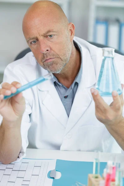 Férfi kutató holding lombikot kék folyadék a laborban — Stock Fotó