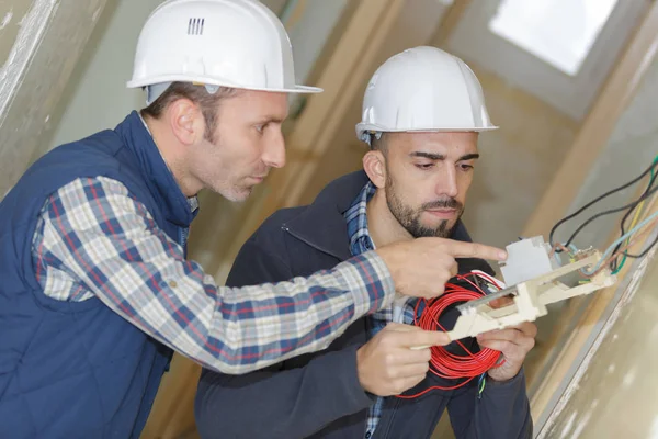 Electricista con aprendiz trabajando en un nuevo hogar —  Fotos de Stock