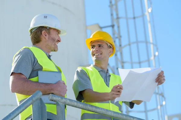 Male workers looking at plans on outdoor site — Stock Photo, Image