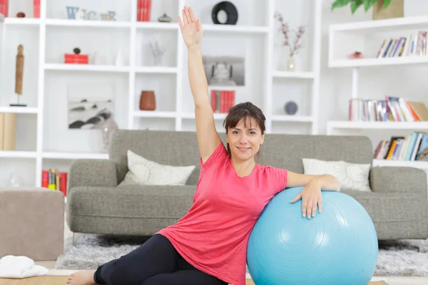 Kvinna gör övningar med bollen på en matta hemma — Stockfoto