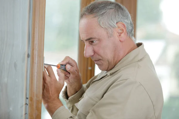 Homme visse un tournevis dans le mur en bois — Photo