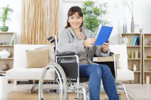 Szczęśliwa młoda niepełnosprawna kobieta na wózku inwalidzkim z książki — Zdjęcie stockowe