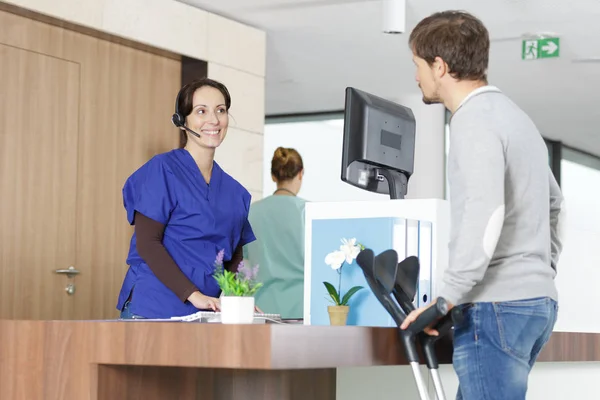Sjukhus receptionist pratar med manlig patient — Stockfoto