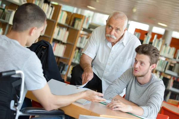 Jeune étudiant joyeux et professeur à la bibliothèque — Photo