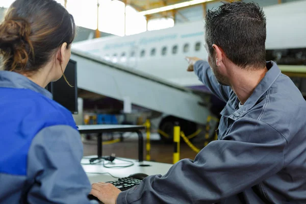 Dois modernos engenheiros de aeronaves apontando um avião — Fotografia de Stock