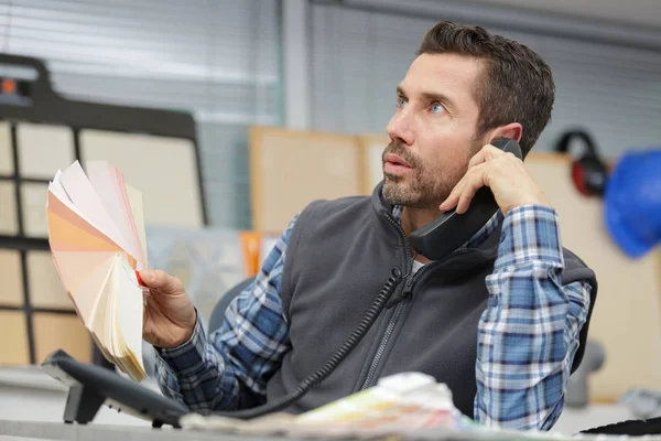 Designer hält Farbmuster in der Hand und telefoniert — Stockfoto