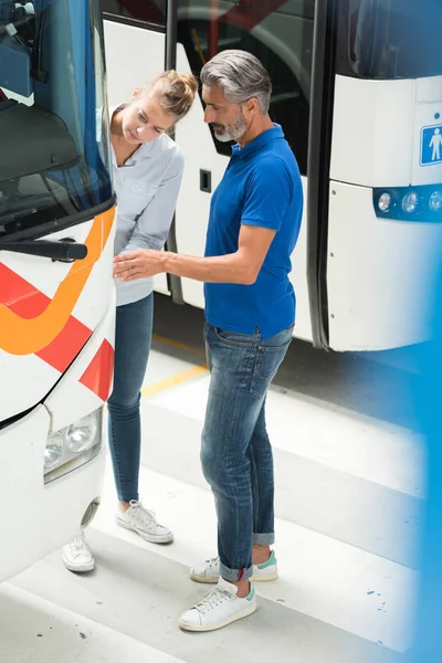 Homem e mulher inspecionando ônibus no depósito — Fotografia de Stock