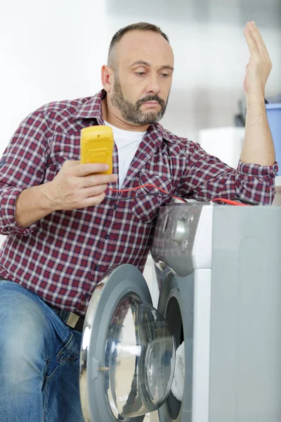 Man is fixing a problem on a clothes washer — Stock Photo, Image