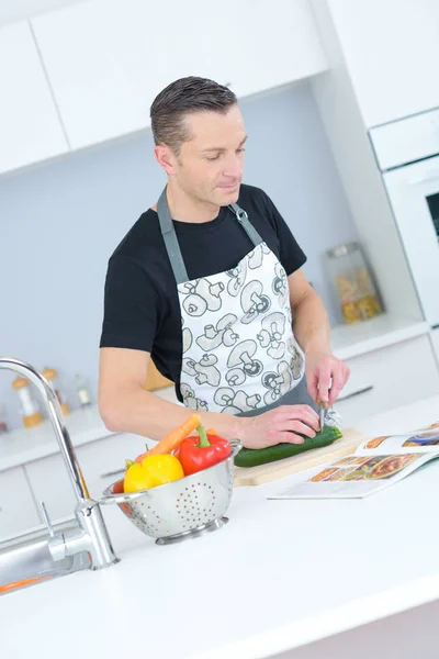 Man following recipe and chopping courgette — Stock Photo, Image