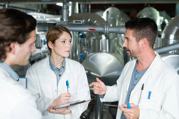 Worker giving tour of factory premises vats in background — Stock Photo, Image
