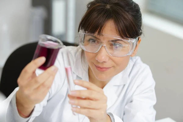 Female medical worker compares test tubes with biological samples — Stock Photo, Image