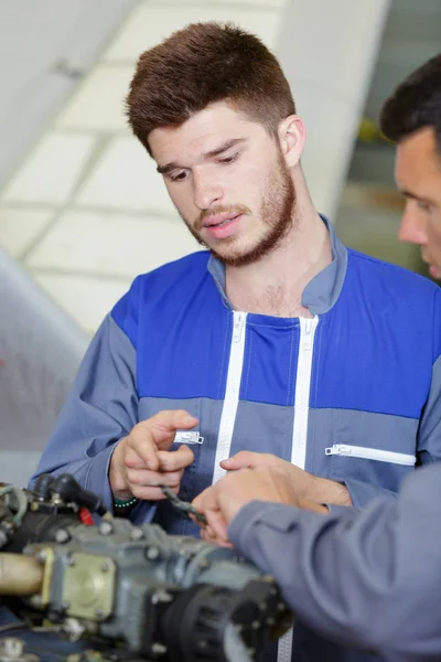 Jonge monteur helpt bij het assembleren van onderdelen — Stockfoto