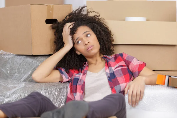 Mujer cansada apoyada en su mano junto a cajas móviles — Foto de Stock