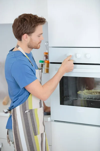 Homem cozinhar algo no forno em casa cozinha — Fotografia de Stock