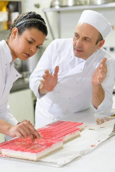 Chef parlant à un apprenti plateau de décoration de desserts — Photo