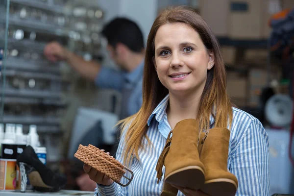 Mujer por zapateros taller celebración reparado botas y cinturón —  Fotos de Stock