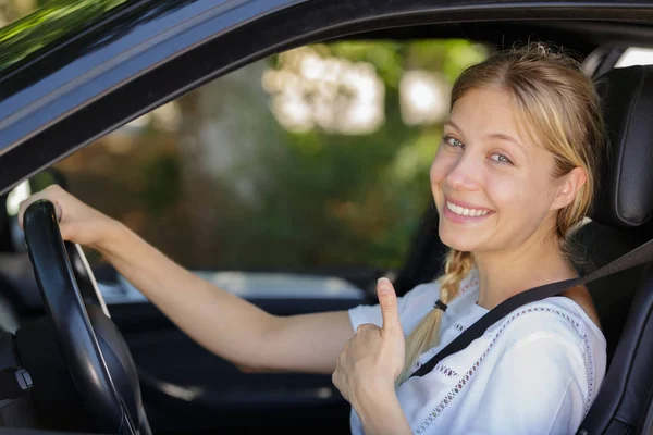 Young woman shows thumbs up in her car — Stock Photo, Image