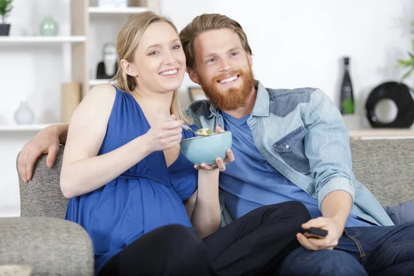 Casal comendo e assistindo a um filme no sofá — Fotografia de Stock