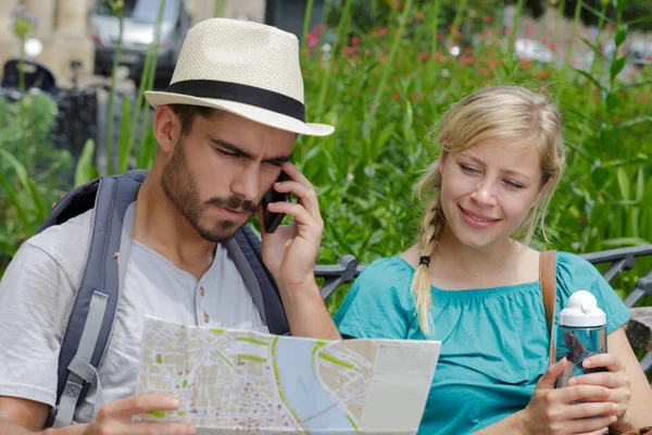 Beautiful tourist couple traveling using map and phone — Stock Photo, Image