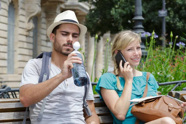 Couple of traveling hipsters sitting on bench — Stock Photo, Image