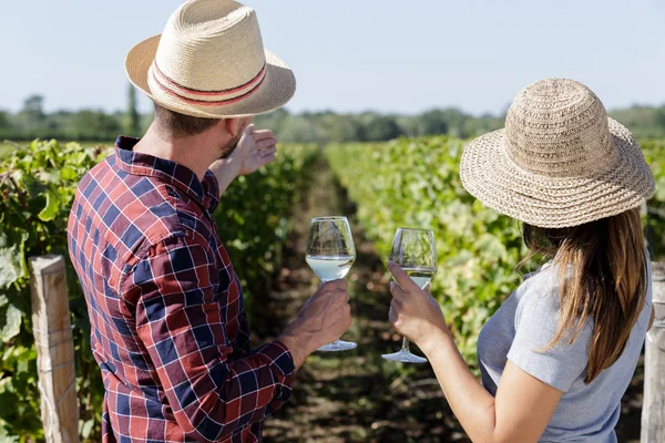 Weinarbeiter und Frau mit Strohhut, die Wein im Glas hält — Stockfoto