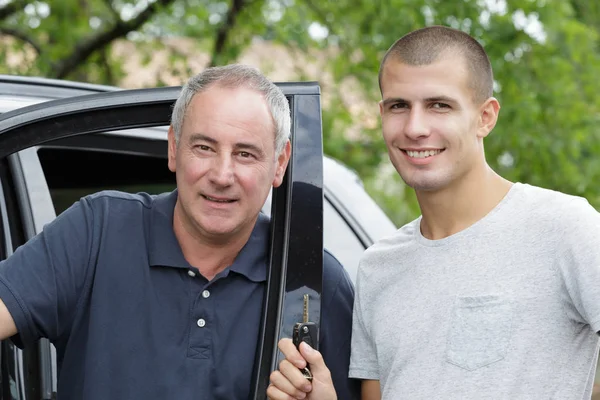 Отец и сын у двери автомобиля сын держит ключи — стоковое фото