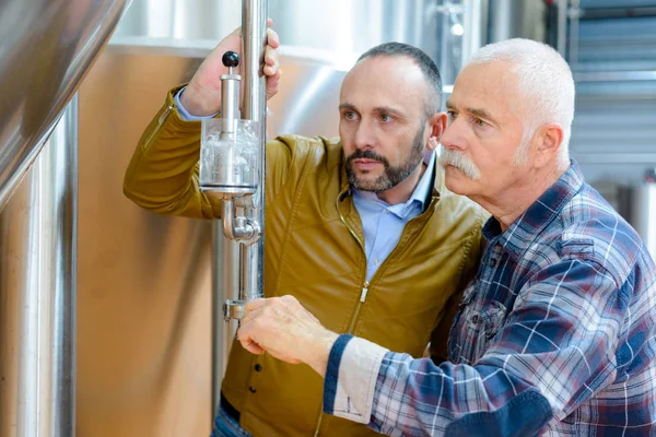 Brewery workers pouring beer into a glass — Stock Photo, Image