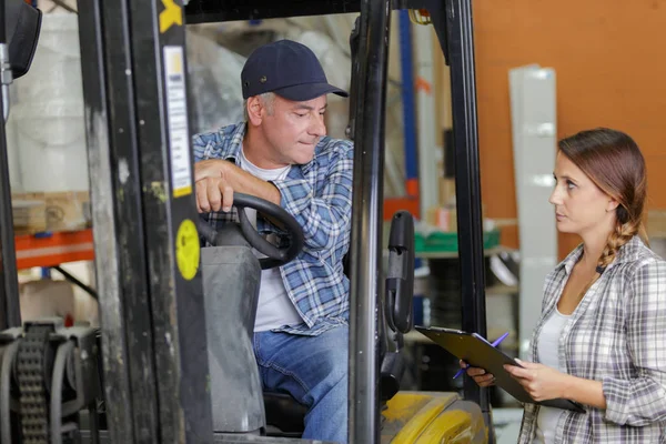 Motorista de empilhadeira conversando com seu gerente em um grande armazém — Fotografia de Stock