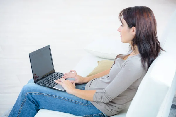 Όμορφη γυναίκα με φορητό υπολογιστή στον καναπέ στο σπίτι χρησιμοποιώντας το Διαδίκτυο — Φωτογραφία Αρχείου