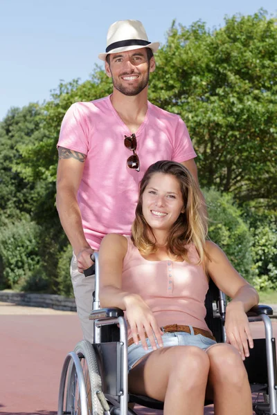 Mujer en silla de ruedas con hombre guapo en el parque —  Fotos de Stock