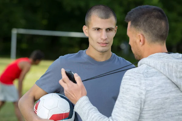 Bola de futebol e treinador durante o treinamento — Fotografia de Stock