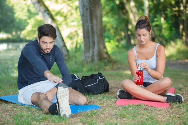 Joven pareja estirándose en el parque — Foto de Stock