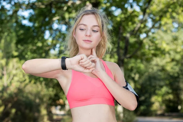 Porträtt av en ung Fitness flicka kontrollera hennes hjärtfrekvens — Stockfoto