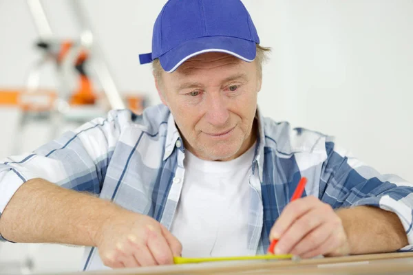 Mann misst Holz mit Maßband — Stockfoto