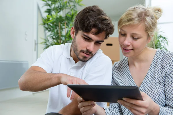 Couple just moved in looking at a tablet — Stock Photo, Image
