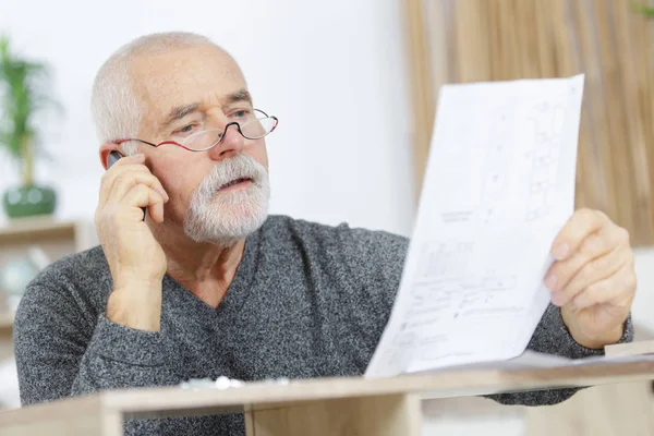 Senior Carpenter aan de telefoon voor het monteren van een meubel — Stockfoto