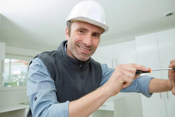 Retrato do homem usando chave de fenda na cozinha — Fotografia de Stock